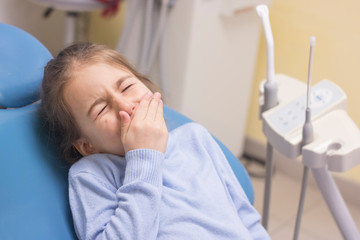 Little girl with toothache in the dentist's chair
