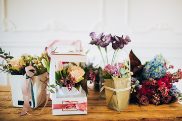 flower abundance. boxes of flowers stand on a wooden table. flower shop. counter in the flower shop. gift for mothers day. flowers for valentines day. flowers on a wooden table.