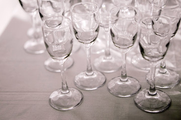 many empty liquor glasses many empty champagne glasses close up. glass goblets on the white table. Empty crystal wineglass. glass goblet on a high leg.