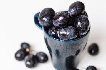 A bunch of big black grapes in a blue cup
