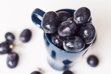 A bunch of big black grapes in a blue cup