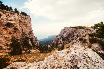 Legs tourist against the backdrop of mountains. mountain landscape in the sun. mighty mountains. view from the mountains to the sea. rocky mountains and blue sky. Clouds hung over the mountains.