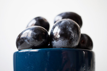 A bunch of big black grapes in a blue cup