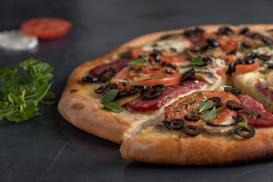 Hot sliced pizza, cheese bacon tomatoes, ham. on a dark Board.
