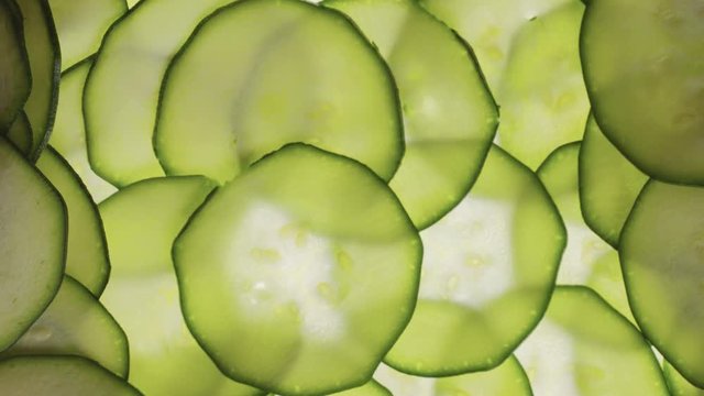 Frame full of zucchini slices and it pushed from sides. Backlight zucchini slices. Green vegetables video closeup