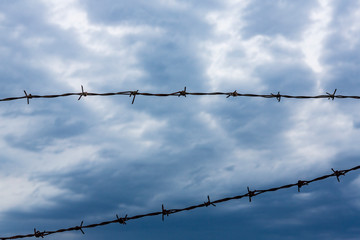 fence of barbed wire against the background of a beautiful blue sky.rusty fence of barbed wire...
