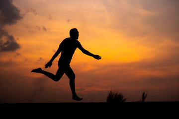 Fototapeta na wymiar Man running alone at beautiful sunset in the road at park . Summer sport and freedom concept. Athlete training on dusk. - Image
