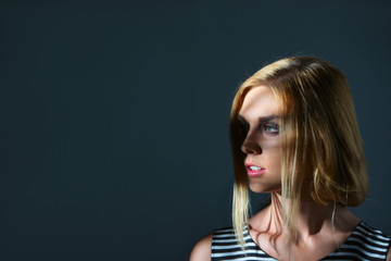 Fototapeta premium Low key portrait of pretty girl in profile with rays of light over the face. Photo with place for text.