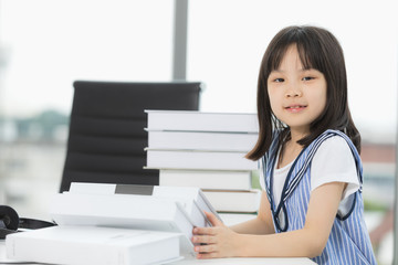 Asian girl smiles to camera, she sitting at table..