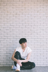 Fototapeta na wymiar Asian model man sitting on floor and knee up..