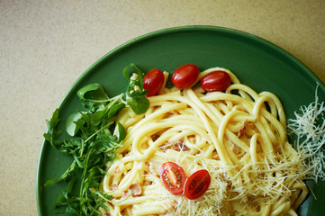 Pasta Carbonara with grated Parmesan cheese and cherry tomatoes, decorated with arugula. Italian lunch.