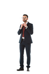 serious businessman in black suit touching tie and looking away isolated on white