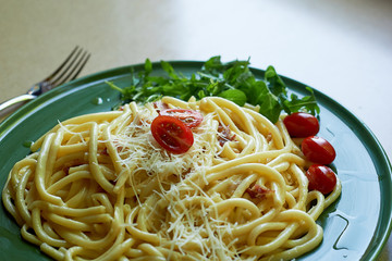 Pasta Carbonara with grated Parmesan cheese and cherry tomatoes, decorated with arugula. Italian lunch.