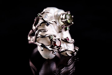 A ring in a silver frame with semiprecious stones on a black background