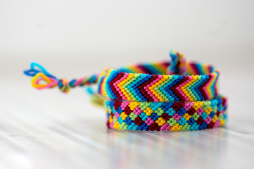 Two handmade homemade colorful natural woven bracelets of friendship isolated on light wooden background, rainbow bright colors