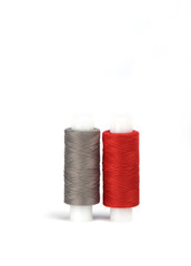 Cotton red and gray threads on the plastic sleeve for the sewing machine.