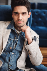 Fototapeta premium Handsome young business man sitting in chair indoors in office.