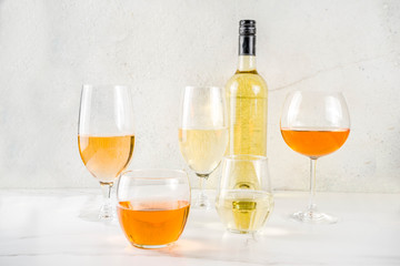 Trendy orange wine, with white wine in different glasses, white concrete background copy space