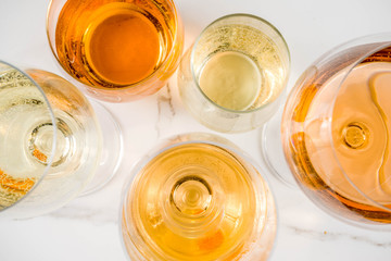 Trendy orange wine, with white wine in different glasses, white concrete background copy space