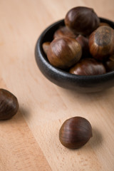 Maronen Esskastanien in schwarzer Schale auf Holz Hintergrund 