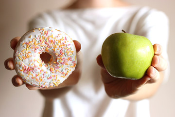 donut and apple in female hands. Healthy and unhealthy food. choice.