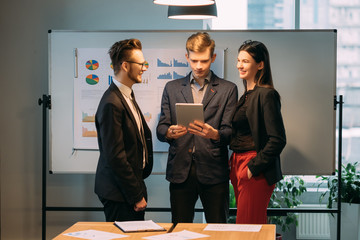 Modern corporate meeting. Information technology. Young team standing in conference room, discussing business strategy.