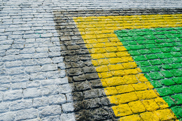 Close-up roapd aving slabs by mosaic construction. Yellow, green, black, white paving cobbles.