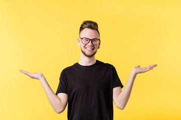 Portrait of cheerful millennial guy smiling, showing both hands open palms, comparing your options....