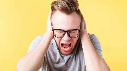 Stop talking. Portrait of frustrated hipster guy covering ears. Mad young emotional man screaming...
