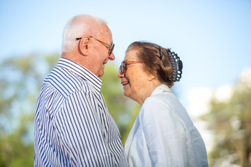 Cheerful senior couple having good time in city park, walking, laughing and enjoying sunny day. Old...