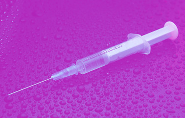 Drug concept, addiction. Syringe on a dark background with water drops. Duotone effect.