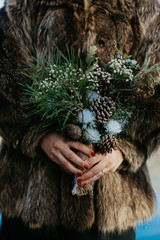 a bride in a fur coat holding a winter bridal bouquet
