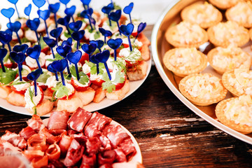 smorgasbord. buffet breakfast. catering services. small sandwiches, cheese and grapes on a skewer, small pies, cherry tomatoes with greens, olive with meat, a cheese plate.