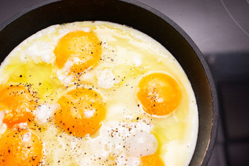 Fried eggs are cooked in a pan on the stove