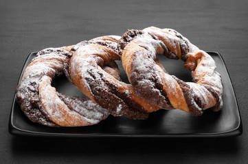 Chocolate cookie rings sprinkled with powdered sugar.