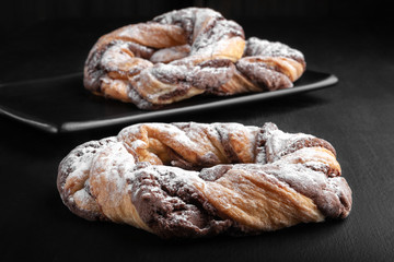 Close-up chocolate cookie rings sprinkled with powdered sugar.
