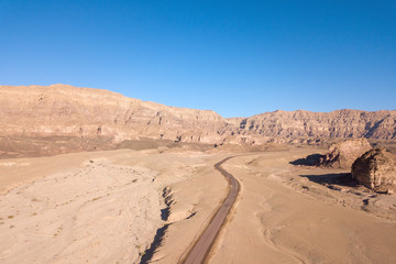 Fototapeta na wymiar Long stretch of an old Desert road with mountains and blue sky in the background, Aerial image.