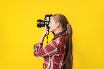 Young female photographer on color background