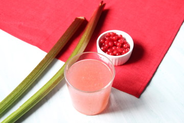 Glass of jelly  made of rhubarb and  currant on white and red background