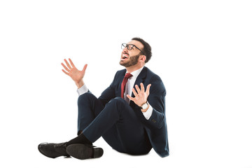 happy businessman looking up and gesturing while sitting on white background