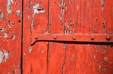 background of a piece of old wooden shutters with cracked red paint