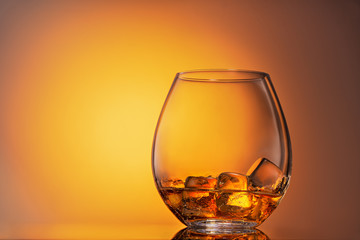 glass of whiskey Scotch with ice on an orange background