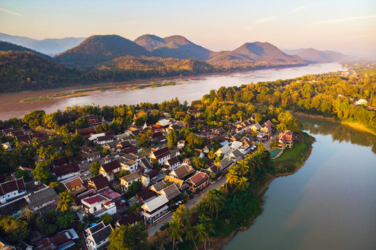 Aerial view of Luang Prabang and surrounding lush mountains of Laos. Nam Kahn River, a tributary of the Mekong River, flows peacefully on the right.