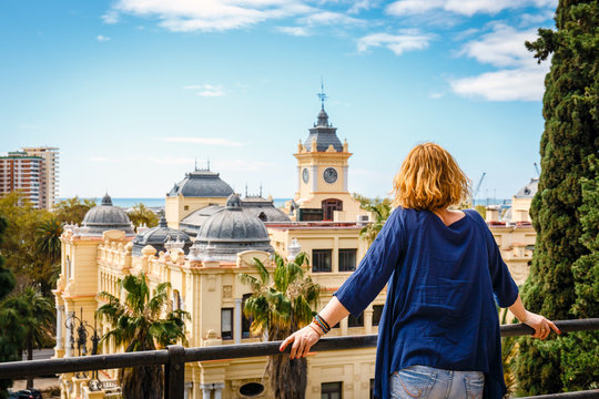 woman with blue shirt enjoys the view over the town of Malaga, Spain
