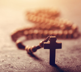 Cross and wooden rosary on stone background.