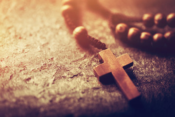 Rosary with wooden cross on stone background.