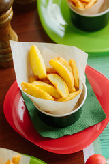 Fried potatoes rolled in parchment over a table.