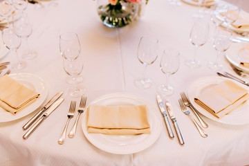 table setting. white porcelain plate on a white tablecloth with a napkin.