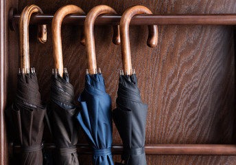 Different classic wooden handle walking length umbrellas on display in luxury clothing boutique...