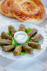 Dolma - rolls made from grape leaves and meat, on white plate.
